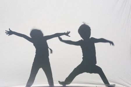 Shadows of a two children boy and girl behind a sheet