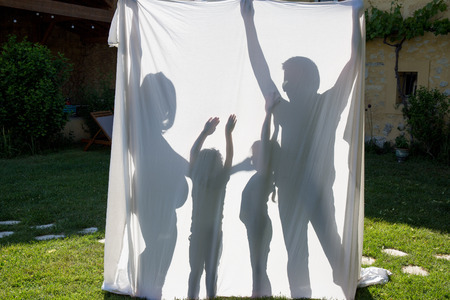 Shadows of a family behind a sheet -Symbol of a familyの写真素材