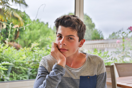 A handsome thoughtful teen sitting on windowの写真素材
