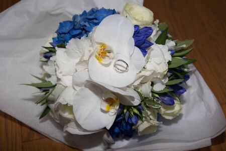 Blue and white flowers and wedding rings on a boardの写真素材