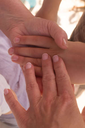 Hands of an elderly woman holding the hand of a baby and a younger woman.の写真素材