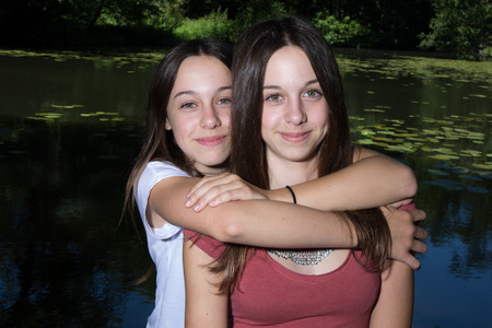 Attractive twins sisters. Close up of two beautiful smiling young women standing togetherの写真素材