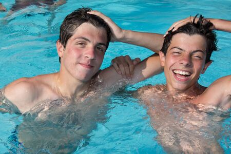 Two brothers in swimming pool having funの写真素材