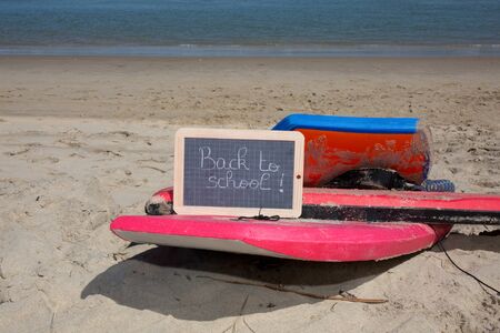Back to school sign on the beach sand and body boardの写真素材