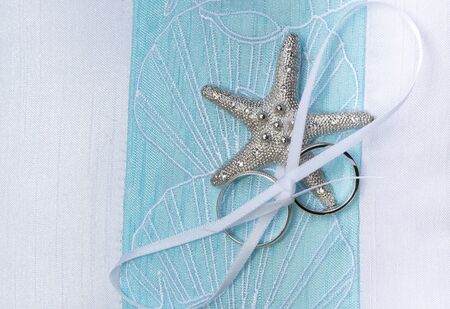 wedding rings on cushion with starfishの写真素材