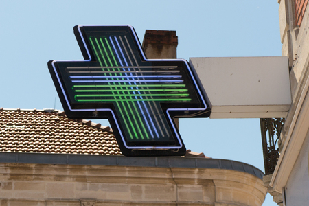Pharmacy sign on the street. Green pharmacy cross on a background of the building.の写真素材