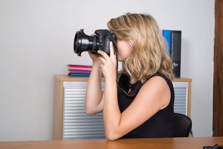 Photographer woman girl is holding a camera taking photographsの写真素材