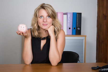 Happy young blonde woman having a piggybank in her handの写真素材