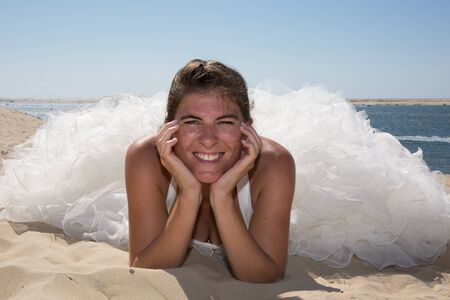 A married woman bride in her wedding dress in sunshine on a beautiful tropical beachの写真素材
