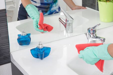Cleaning tap - woman is  cleaning a bathroomの写真素材