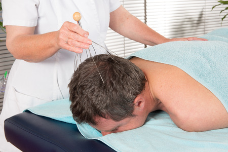 Female therapist doing head massage on man in the spa salon.の写真素材