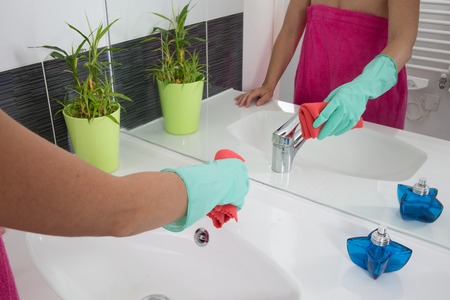 Woman doing chores in bathroom at home, cleaning sink and faucet with spray detergent.の写真素材
