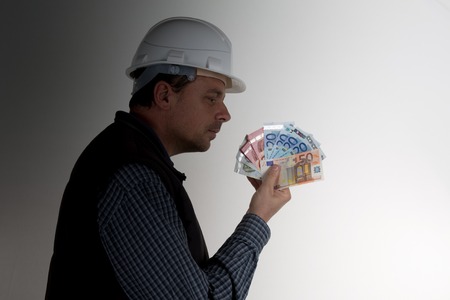 Builder holding wedge of bank notes dirty moneyの写真素材