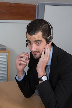 Happy Businessman in the office on the phone, headset, Skype. looking cameraの写真素材