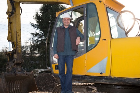 Construction manager controlling building next to a heavy machineの写真素材