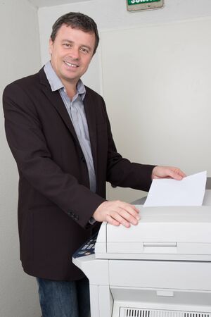 Cheerful man working with printer in the office at work