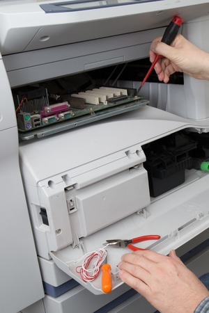 closeup shot hands of technician fixing a broken photocopier machine