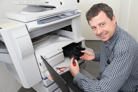 Man technician repairing a printer at business place at work