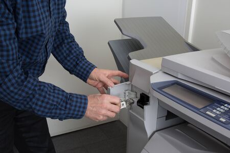 Handyman is fixing the office printer in a bright officeの写真素材