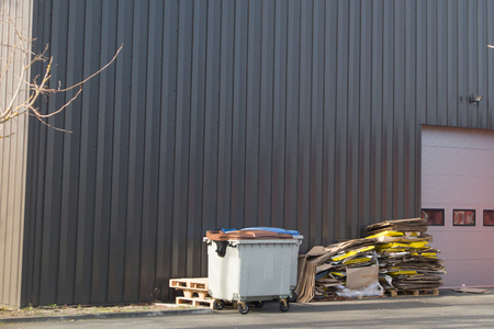 Commercial waste bins in a business park under the grey wall of buildingの写真素材