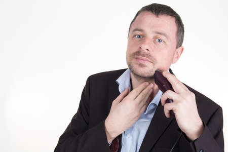 Mid aged business man shaving with electric razor