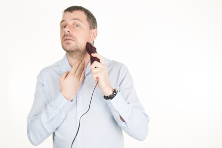 A closeup of a  man shaving his beard off with an electric shaver.