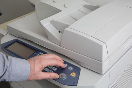Business man with his finger on the start key and ready to make a photocopy