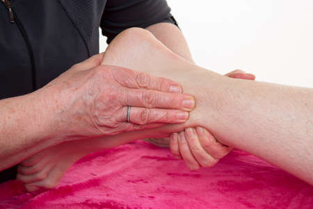 Hands of an osteopath massaging a foot in a roomの写真素材