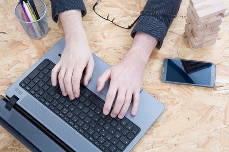 Female hands typing on a laptop keyboard  on a desk with a phone  and glasses