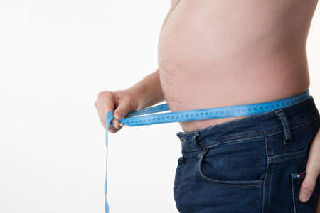 Big belly of a  man and measuring tape isolated on whiteの写真素材