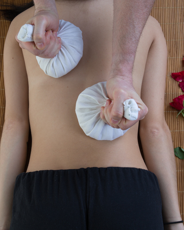 Beautiful young woman getting herbal compress ball therapy at Spa Salonの写真素材