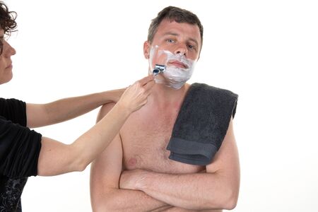 At beauty center a woman is shaving a man isolatedの写真素材