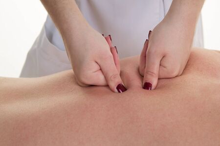 Man's back having a massage with female fist in a spa centerの写真素材