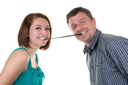 Happy couple looking to the camera with licorice on mouthの写真素材