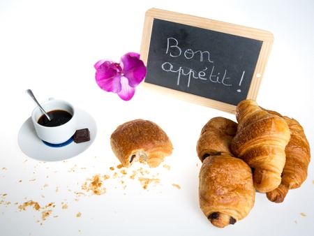 Enjoy your meal in french written with chalk on blackboard with croissant and cup of coffeeの写真素材