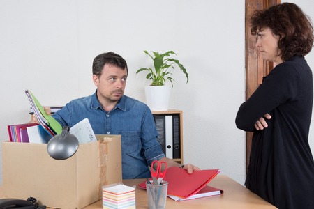 Sad man fired by a woman at officeの写真素材