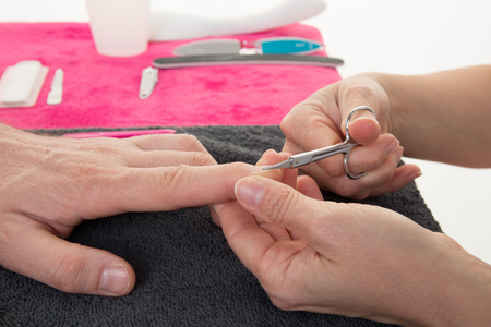 man in a nail salon receiving a manicure by a beauticianの写真素材