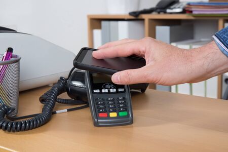 Man paying for good with NFC technology on mobile phone