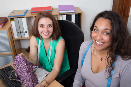 Two multiethnic female fashion designers working at deskの写真素材