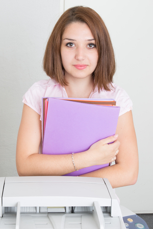 Serious business woman looking at the camera next to a copy machineの写真素材