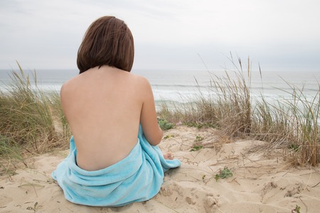 Beautiful woman nude sitting from the back on the beachの写真素材