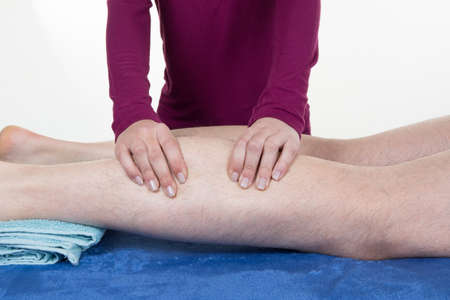 Detail of hands massaging human calf muscle.Therapist applying pressure on female leg.の写真素材