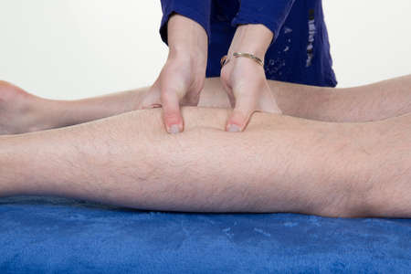 Detail of hands massaging human calf muscle.Therapist applying pressure on male leg.