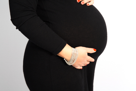 Happy Pregnant woman in a black dress holding her bellyの写真素材