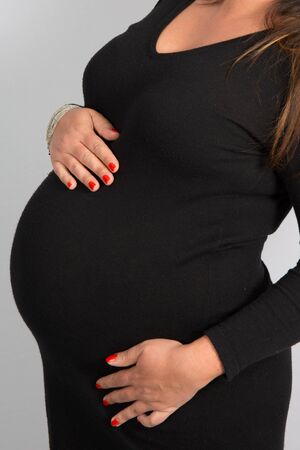 Pregnant woman in a black dress holding her bellyの写真素材