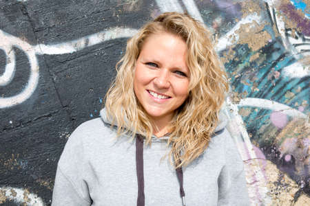 Portrait of beautiful young blond woman in grey blouse posing outdoorsの写真素材