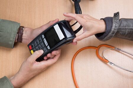 Woman paying the doctor with credit card flat layの写真素材