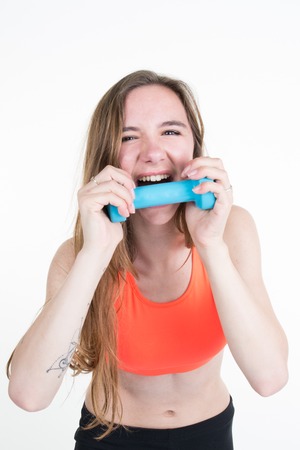 pretty blond woman bites her workout dumbbell.の写真素材