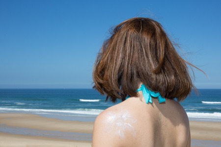 Back view of woman is having sunbathes with sun tan lotion sun drawingの写真素材
