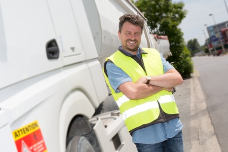 Proud driver or forwarder in front of trucks and trailers, on a transshipment point